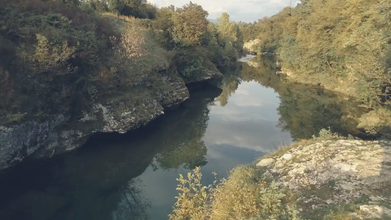 La forra del Natisone in autunno: acqua verde tra rocce chiare e alberi gialli.